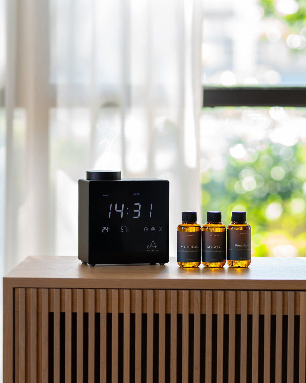 Aromadd diffuser with fragrance oils beside a window